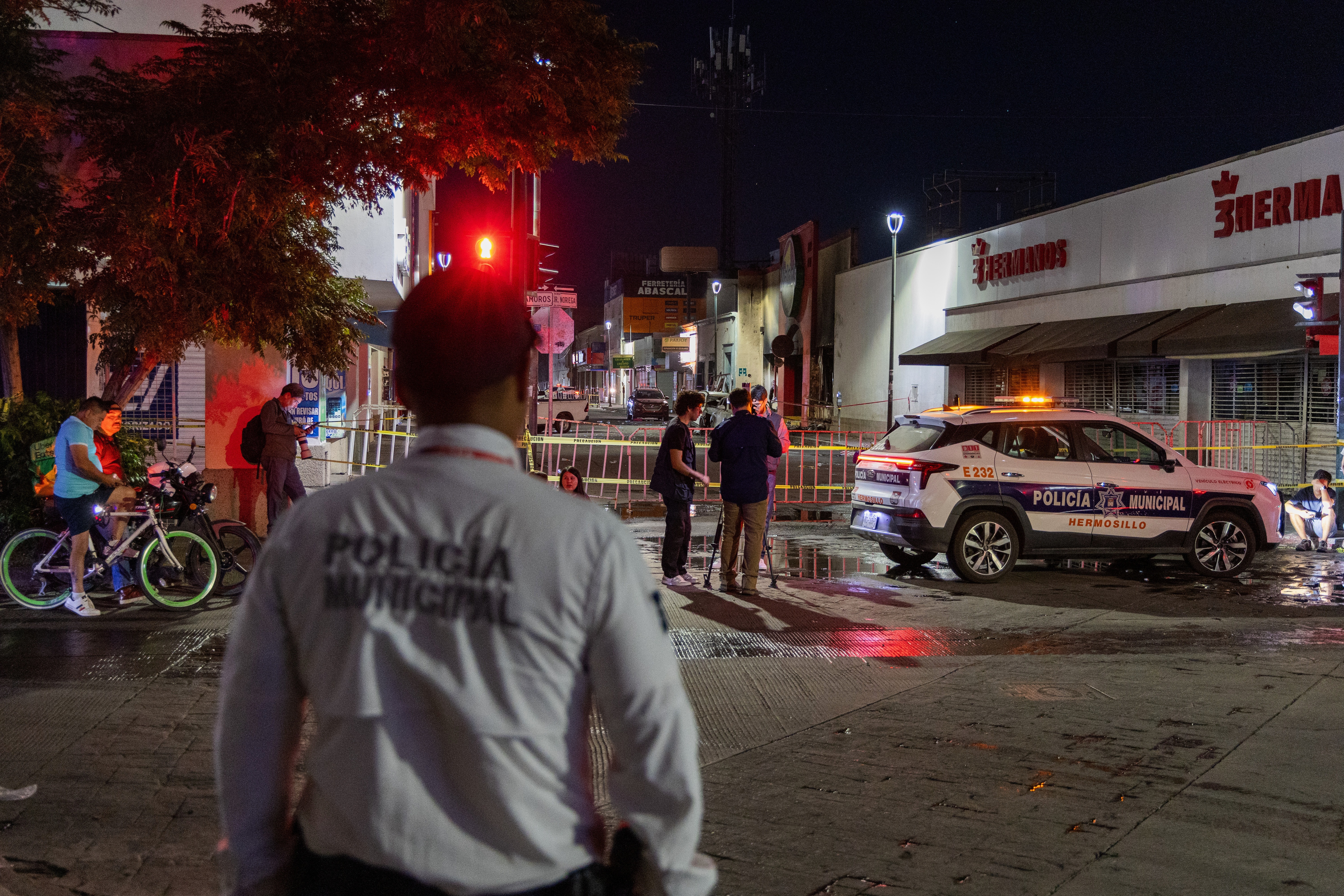 Policeman stands near a convenience store destroyed by a fire in Hermosillo, Sonora state, Mexico, Saturday, Nov. 1, 2025.